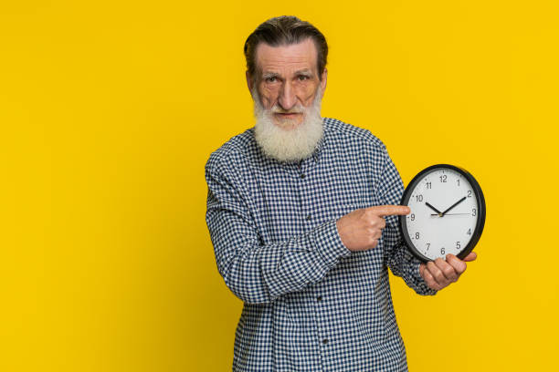 istock Senior old man showing time hour on wall office clock, ok, thumb up, approve, hurry up, deadline 2180109735