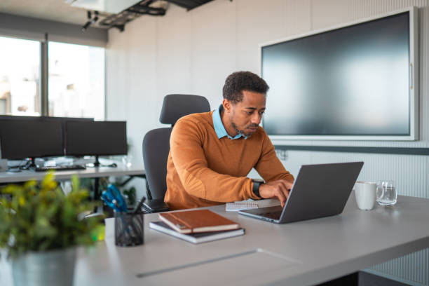 istock Focused Black Businessman Typing on Laptop in Office 2180111884