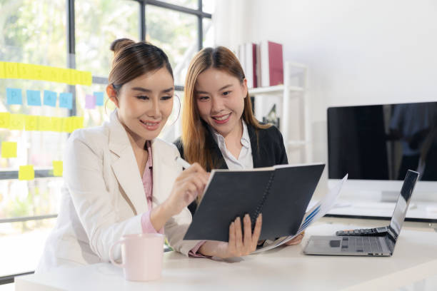 istock Two women talk, discuss, work on new project ideas. Analyze marketing plans and business investments to ensure success. 2180123089