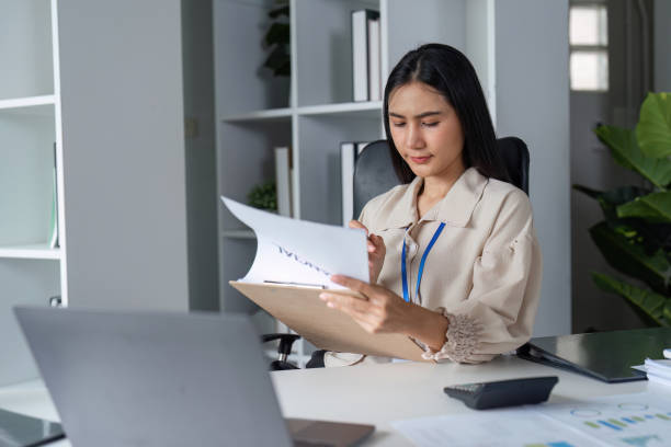 istock Business Professional Analyzing Documents in Modern Office Setting with Laptop and Calculator 2180127944