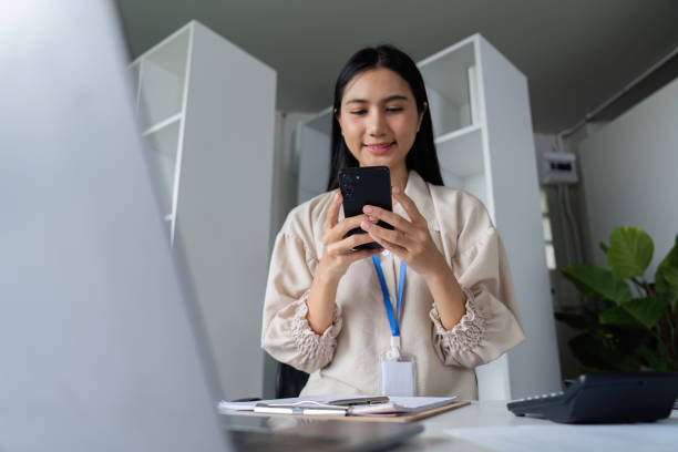 istock Focused Businesswomen Analyzing Documents in a Modern Office Setting with Laptop and Smartphone 2180127967