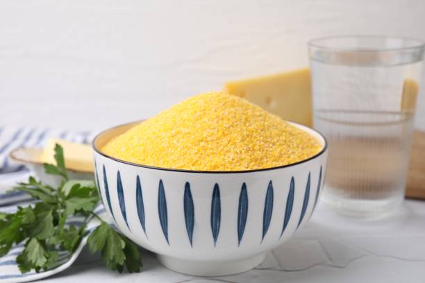 istock Raw cornmeal in bowl and parsley on light table, closeup 2180128709