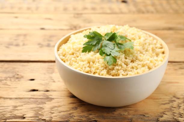 istock Delicious bulgur with parsley on wooden table, closeup. Space for text 2180128736