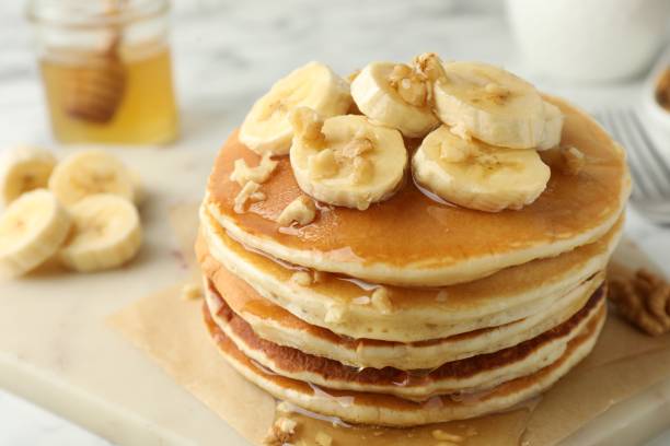 istock Delicious pancakes with bananas, walnuts and honey on table, closeup 2180129952