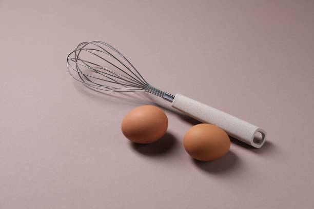 istock Metal whisk and raw eggs on grey background 2180129987