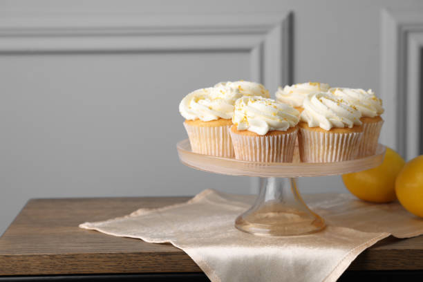 istock Delicious lemon cupcakes with white cream on wooden table, space for text 2180130103