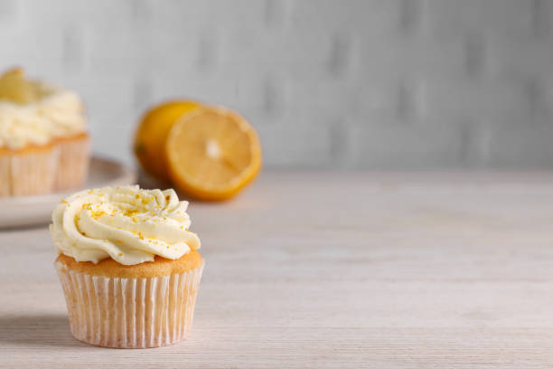 istock Delicious cupcake with white cream and lemon zest on light wooden table, space for text 2180130106