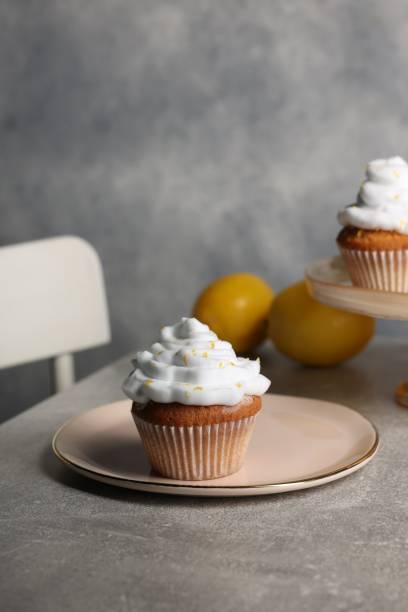istock Delicious cupcakes with cream and lemon zest on gray table, space for text 2180130137