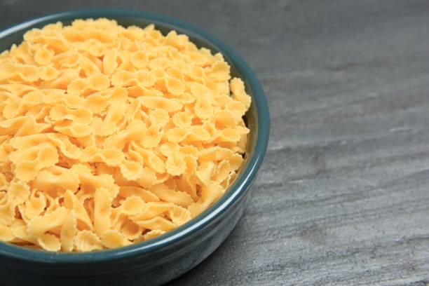 istock Raw farfalline pasta in bowl on grey table, closeup. Space for text 2180130542