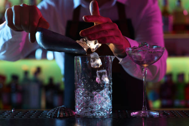 istock Alcoholic cocktail making. Bartender adding ice cubes into mixing glass at counter in bar, closeup 2180130818