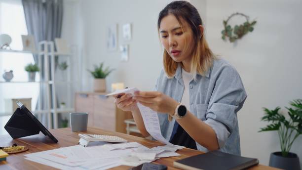 istock Struggle woman having financial problems paychecks paper receipt bill statement ,calculating on calculator monthly expenses debt,planning budgets of monthly personal balance at home. 2180134156