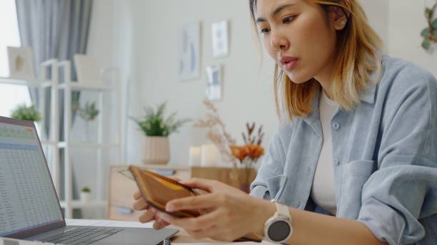 istock Struggle woman opening  wallet  with tiny US dollar having financial problems paychecks paper receipt bill statement ,calculating on smartphone for monthly expenses debt,planning budgets of monthly personal balance at home 2180134204