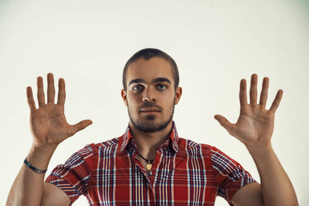Young man wearing a red plaid shirt is pointing to an invisible screen on a white background, as if he is interacting with data or a presentation