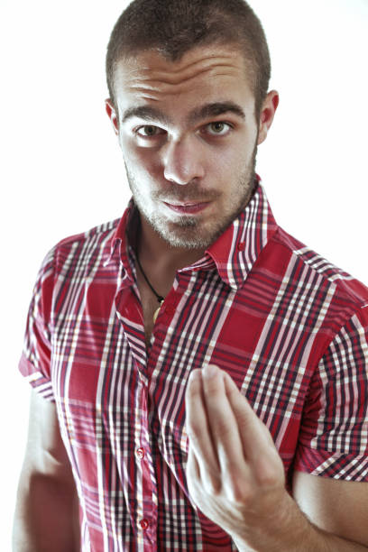 Young man with an intense expression is gesturing with his hand, as if beckoning or summoning. His serious demeanor suggests a sense of purpose and determination