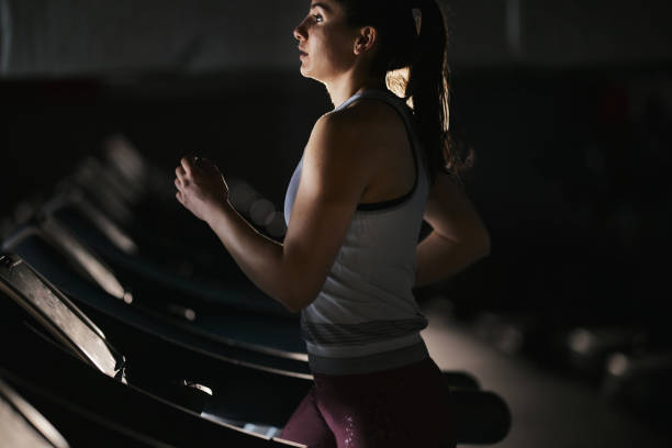 istock Athletic woman jogging on treadmill in a gym. 2180158028