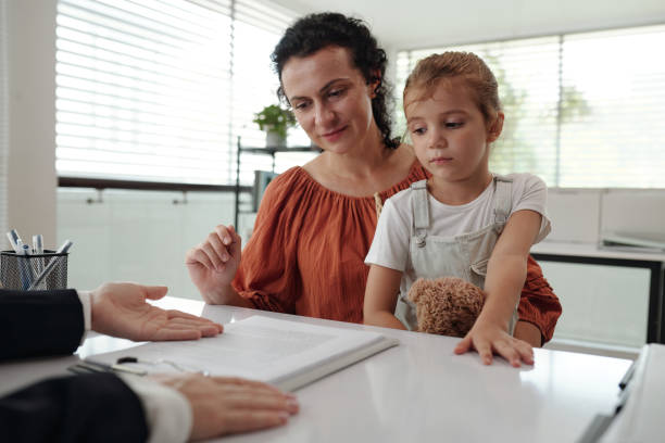 istock Young Mother Signing Application At Social Service 2180159979