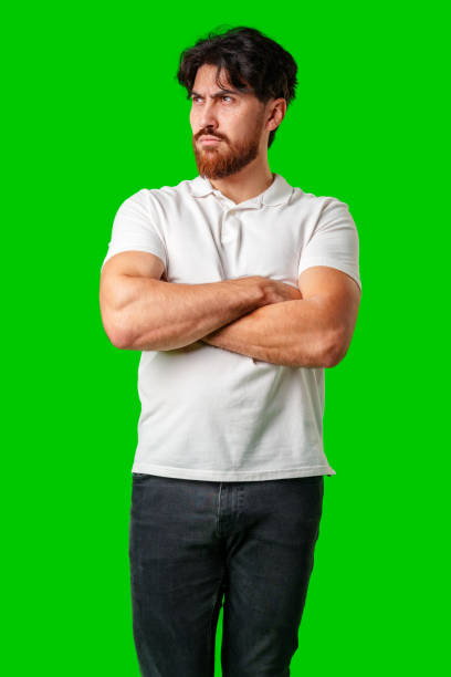istock A man with a serious expression stands with crossed arms against a vibrant green background 2180168972