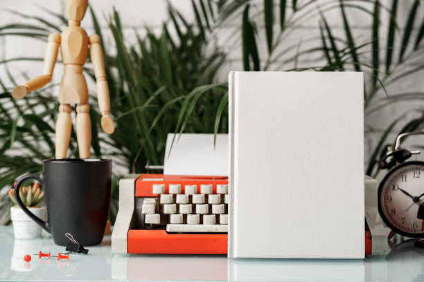 Hardcover book and vintage typewriter on white desk close up