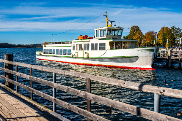 Istanbul, Turkey - December 05, 2025:A passenger ferry cruising through the blue waters of the Bosphorus near a forested shoreline in Istanbul, Turkey, on a clear day. The multi-deck vessel creates a white wake as it moves across the strait, with buildings and green hills visible in the background