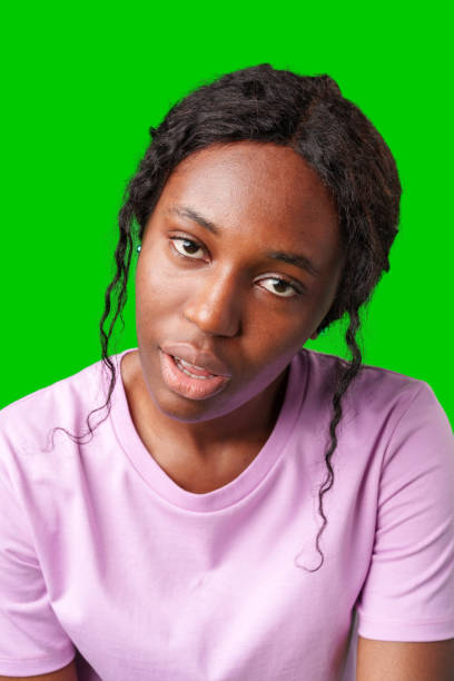 istock Young woman with curly hair shows a skeptical expression against a bright green background 2180174802