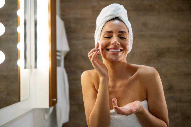 istock Woman happily applies face cream in bathroom setting 2180175488