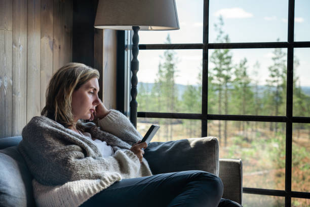 istock Woman Enjoying an E-Reader Book While Relaxing in a Cozy Cabin With Scenic View 2180176066