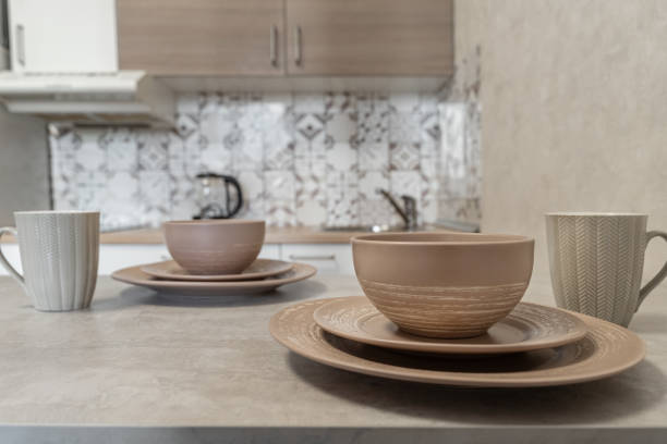 istock design of modern beige kitchen. brown dishes on kitchen table. Plates of different sizes and ceramic mugs. Setting table for breakfast, lunch or dinner. cozy evening at home. Breakfast for two. 2180176605