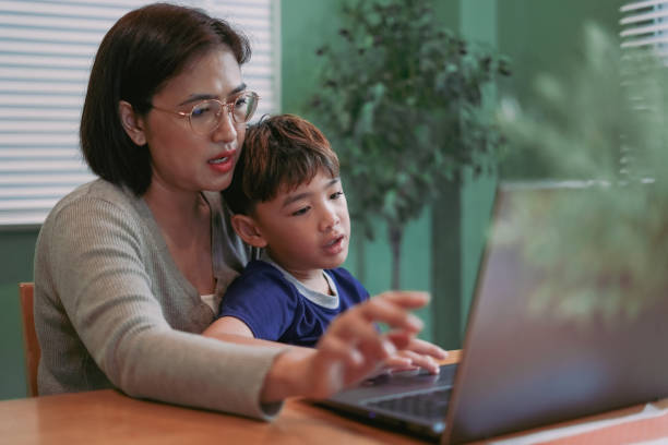 istock Mother teaches her son to learn on the computer laptop 2180181698