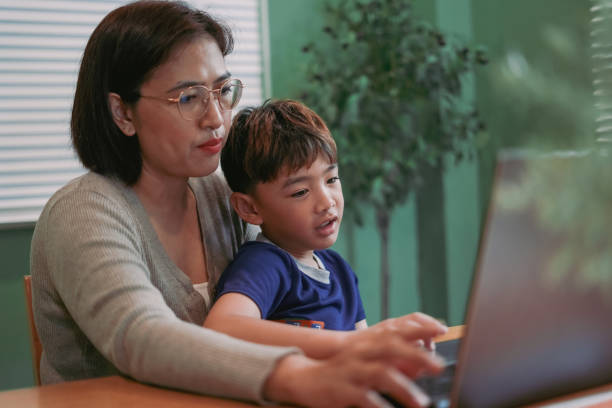 istock Mother teaches her son to learn on the computer laptop 2180181761