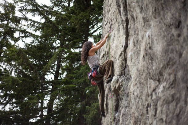 istock Young woman climbs with rope on cliff face 2180187130