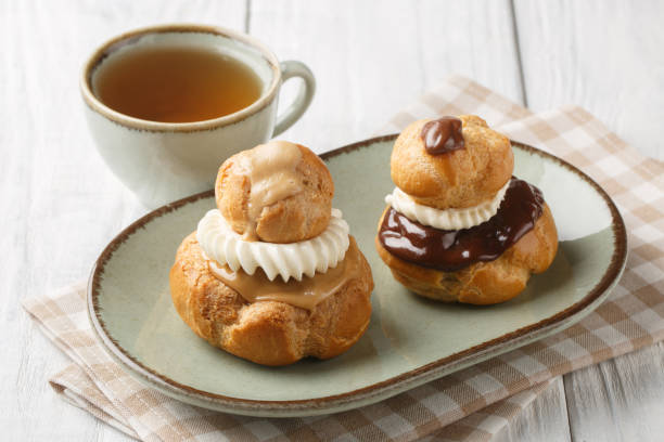 Exquisite Religieuse eclair pastry with patissiere cream with chocolate and coffee glaze close-up in a bowl. Horizontal