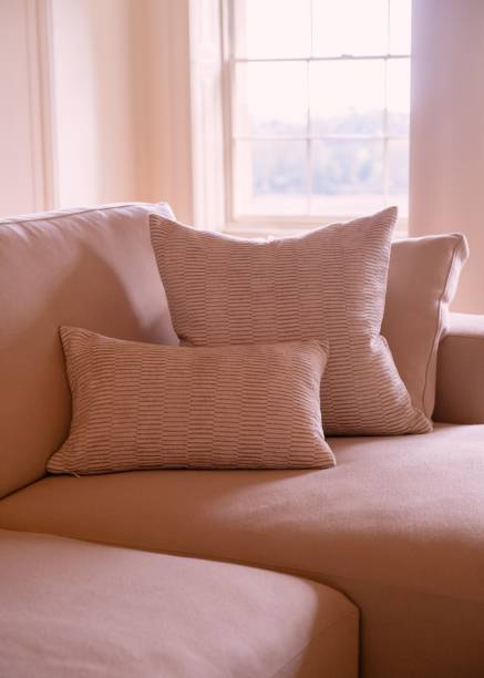 istock Cozy beige sofa with textured pillows by a window. 2180189968