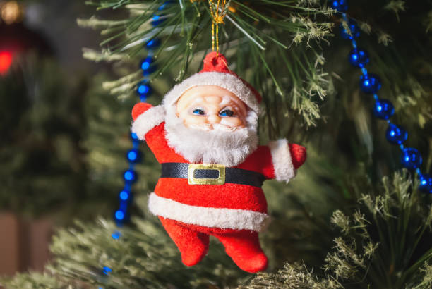 istock Santa Claus doll and blue beads hanging on decorated Christmas tree 2180194049