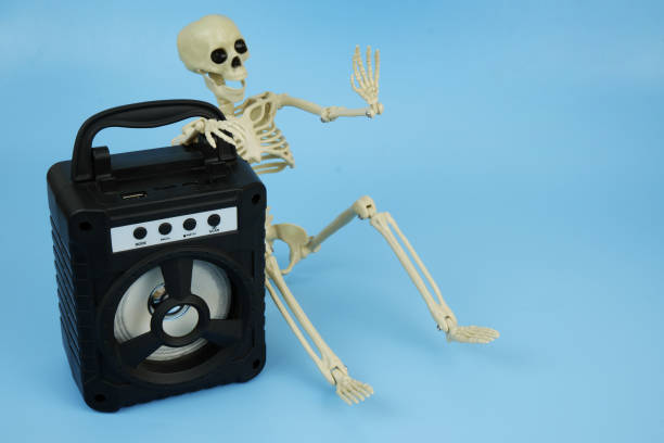 istock Death or human skeleton sitting with black audio speaker on blue background. 2180195141