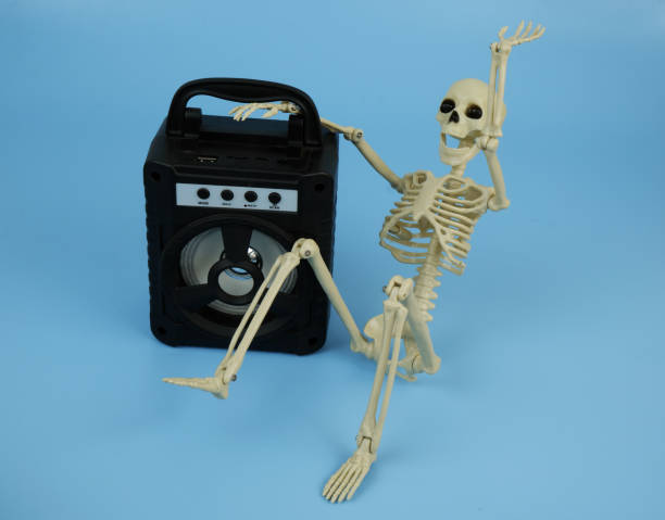 istock Death or human skeleton sitting with black audio speaker on blue background. 2180195150