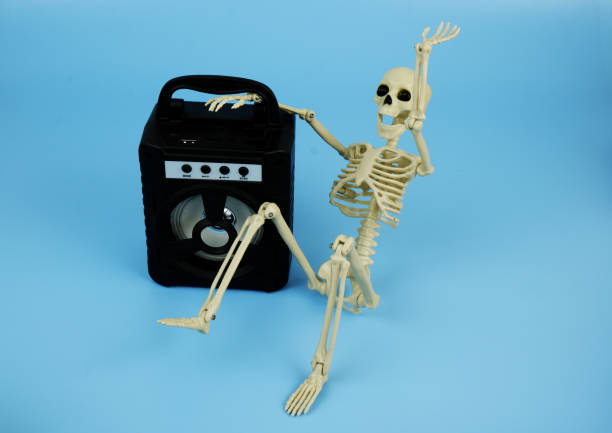 istock Death or human skeleton sitting with black audio speaker on blue background. 2180195151