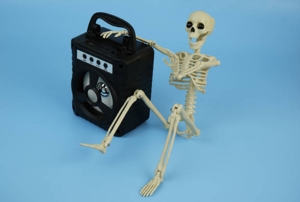 istock Death or human skeleton sitting with black audio speaker on blue background. 2180195152