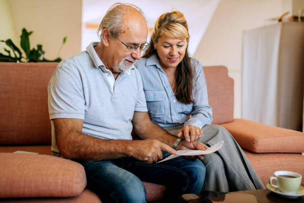 istock Mature couple analyzing bills while sitting on a sofa at home 2180197964