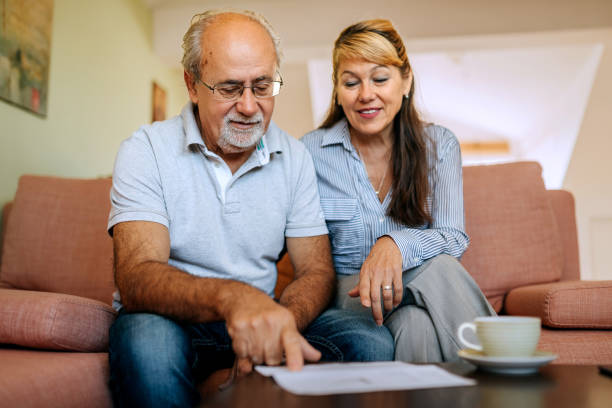 istock Senior couple going over bills while sitting on a sofa at home 2180198046