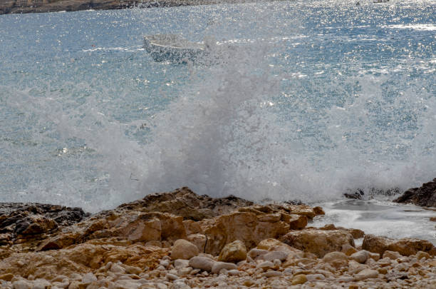 Splash of the sea wave with foam close up. Abstract sea wave background. Waves on the beach in windy day.