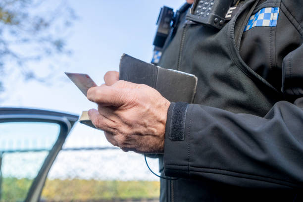 UK police officer taking notes at a parked car.