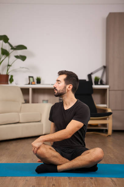 istock Man doing tiwst yoga poses while being home 2180204970
