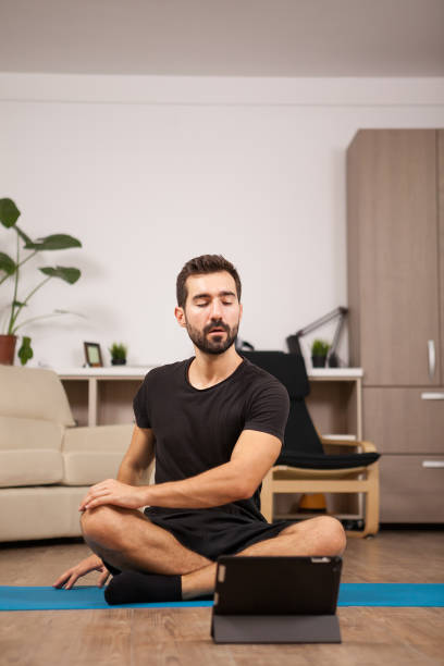 istock Young man watching the game while he's stretching his back on the floor 2180205138