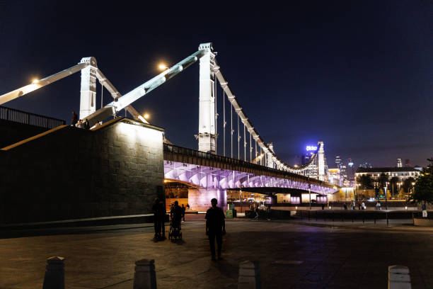 Moscow, Russia, September 29, 2023: Illuminated Krymsky Bridge on the Moskva River at night and promenade on the riverbank