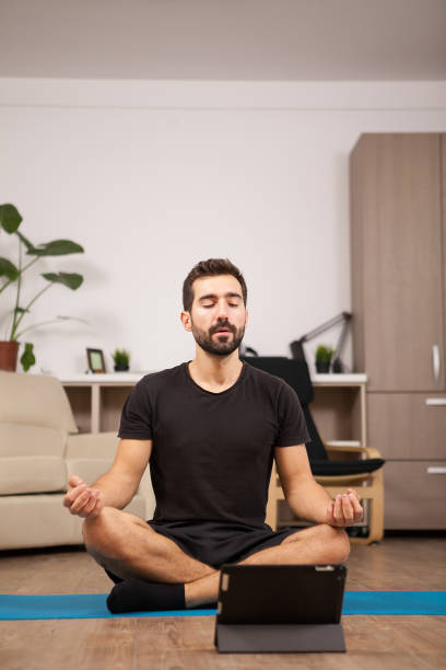 istock Young man watching the game while he's stretching his back on the floor 2180205880