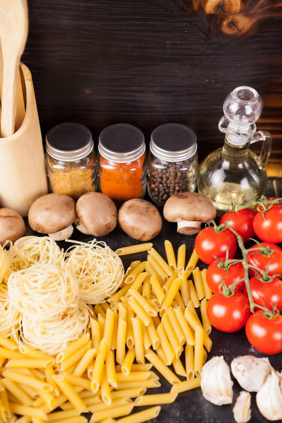 istock Uncooked raw macaroni, pasta and spaghetti next to fresh and healthy vegetables, 2180210249