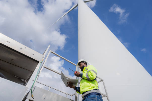 istock A man in a yellow jacket is standing on a platform next to a wind turbine. He is looking at a laptop computer. electrical, engineer, environment, energy, clean, sustainable, wind turbine, nature 2180212846