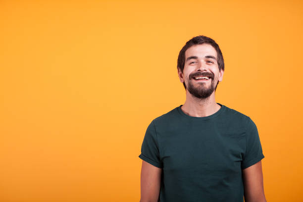 istock Handsome smiling man with arms at his back on orange background 2180213438