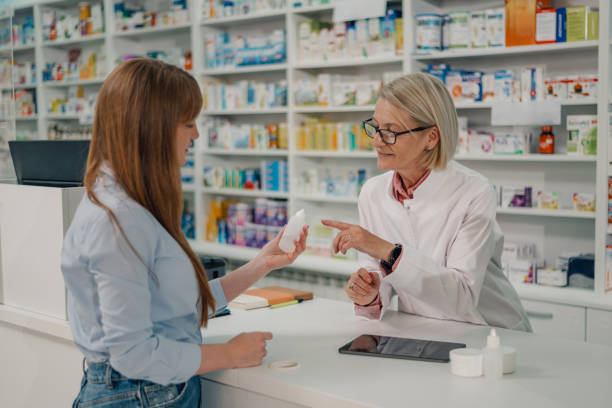 istock Old druggist at pharmacy explaining drug using to a customer with bottle 2180214013