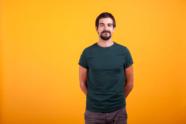 istock Handsome smiling man with arms at his back on orange background 2180214242